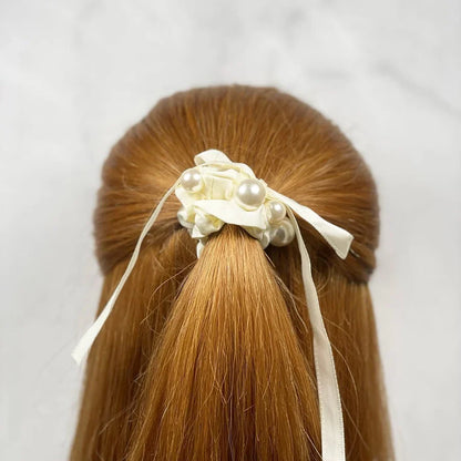 Soft cloth hair scrunchie in cream color with pearl accents tied on red hair ponytail