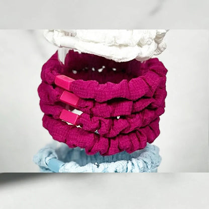 Stack of pink and blue soft cloth hair ties with textured fabric and clips for gentle hair styling
