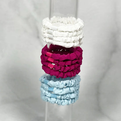 Set of white pink and blue soft cloth hair ties neatly stacked on clear display stand