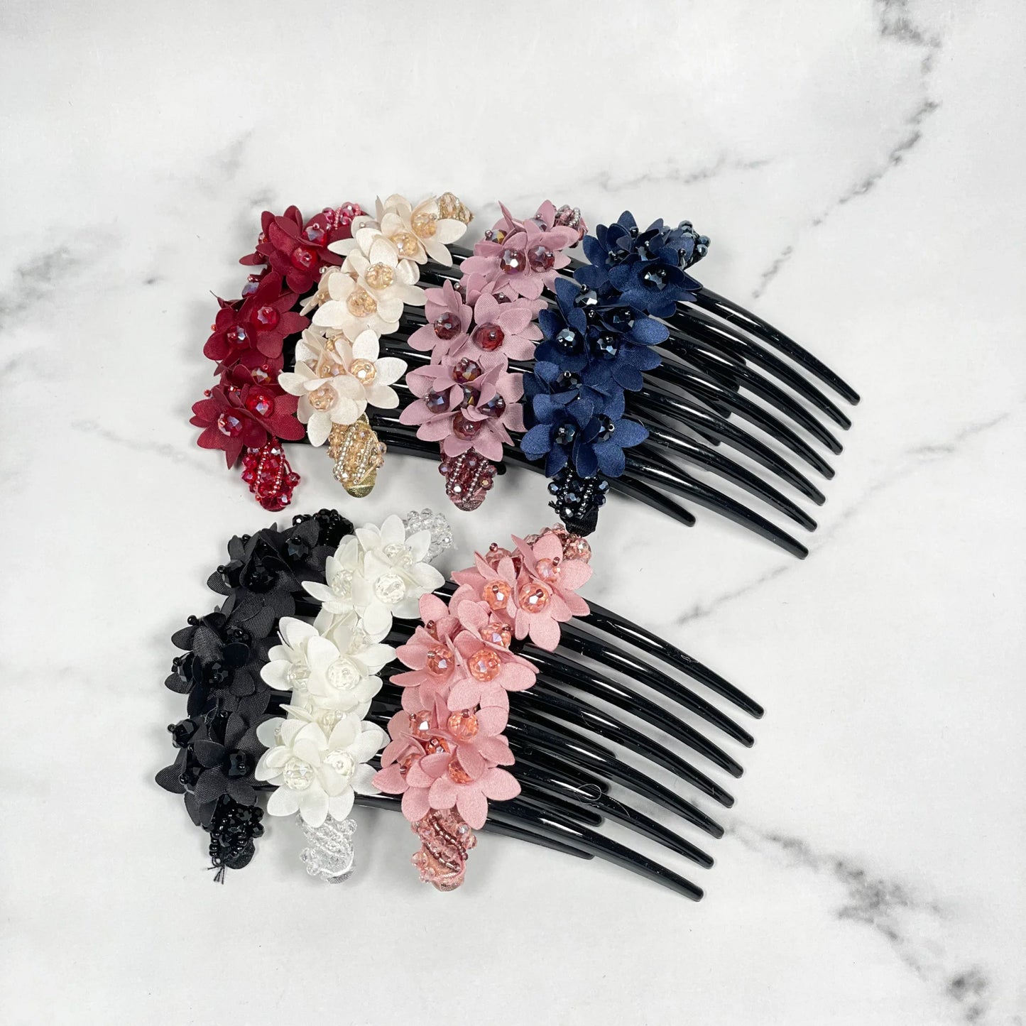 Assorted studded hair bun combs with decorative floral designs in multiple colors on black comb base