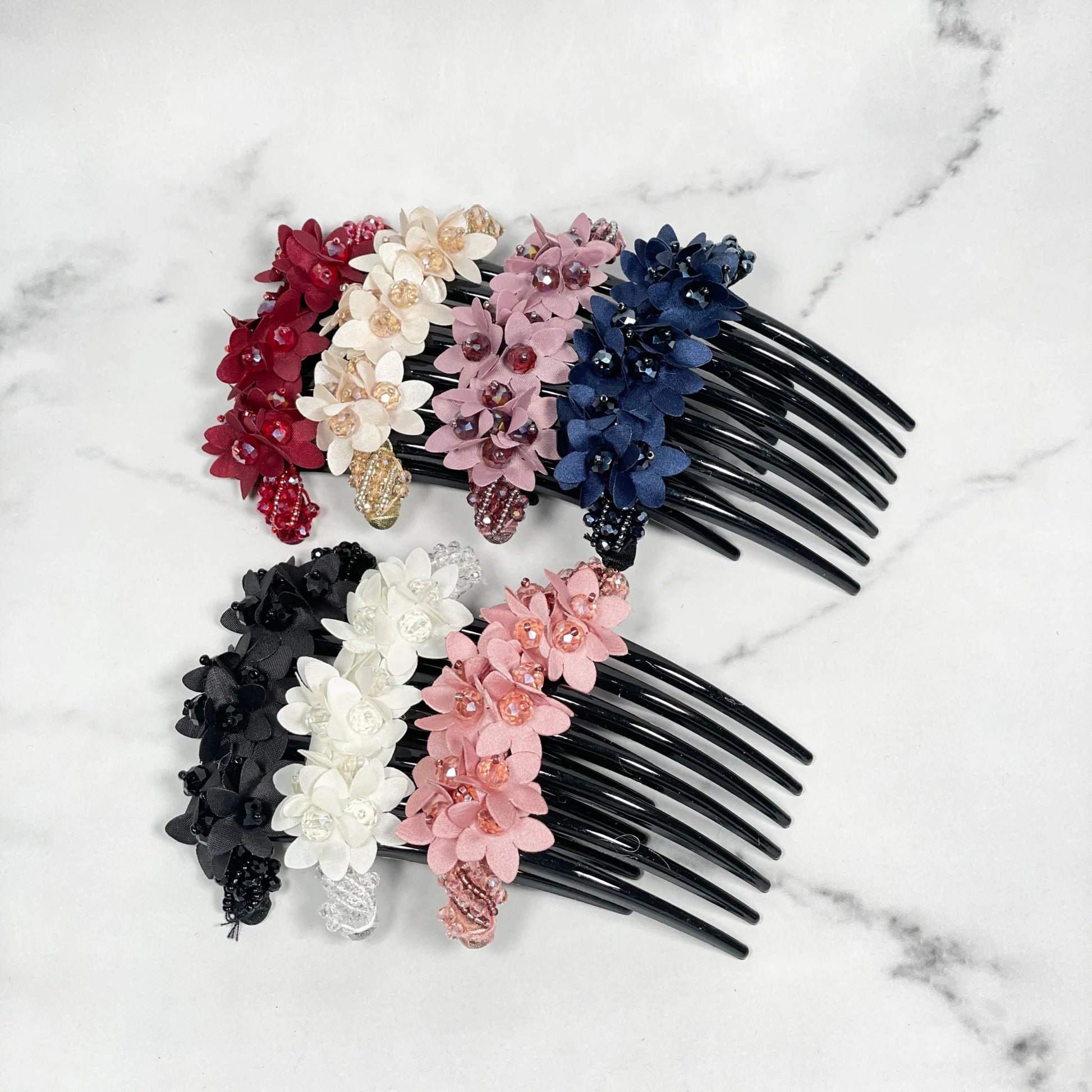 Assorted studded hair bun combs with decorative floral designs in multiple colors on black comb base