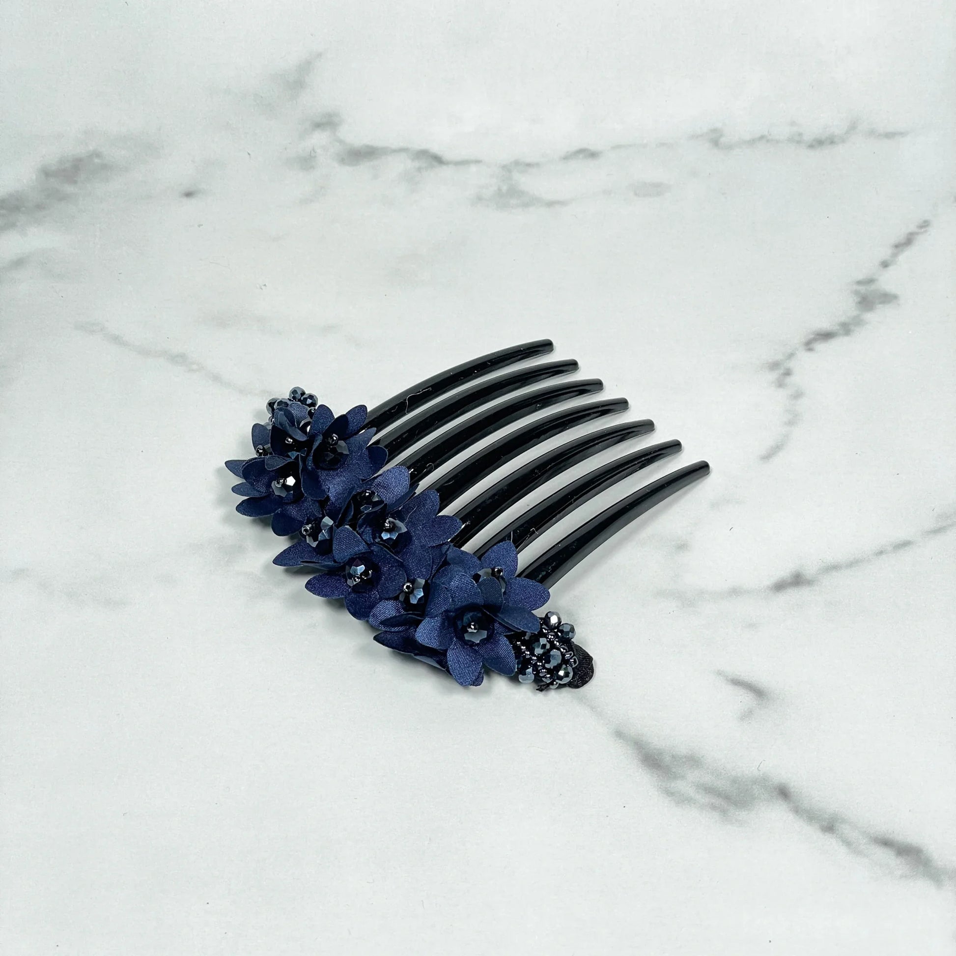 Black studded hair bun comb decorated with blue fabric flowers and small black beads