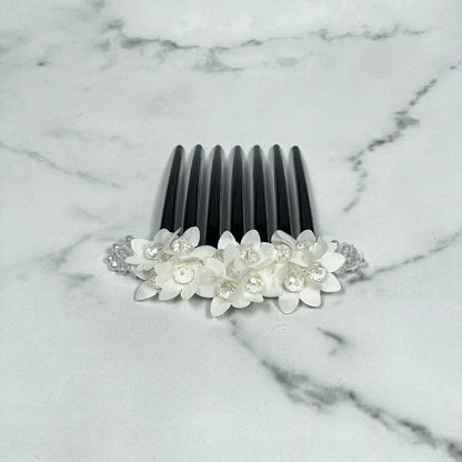 Studded hair bun comb with white floral decorations and clear rhinestones on black plastic comb