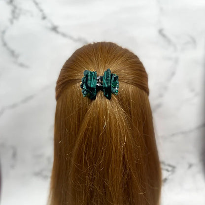 Green studded hair clutches securing half-up hairstyle on long light brown hair