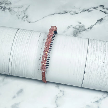 Pink studded headbands with decorative beads displayed on white textured surface