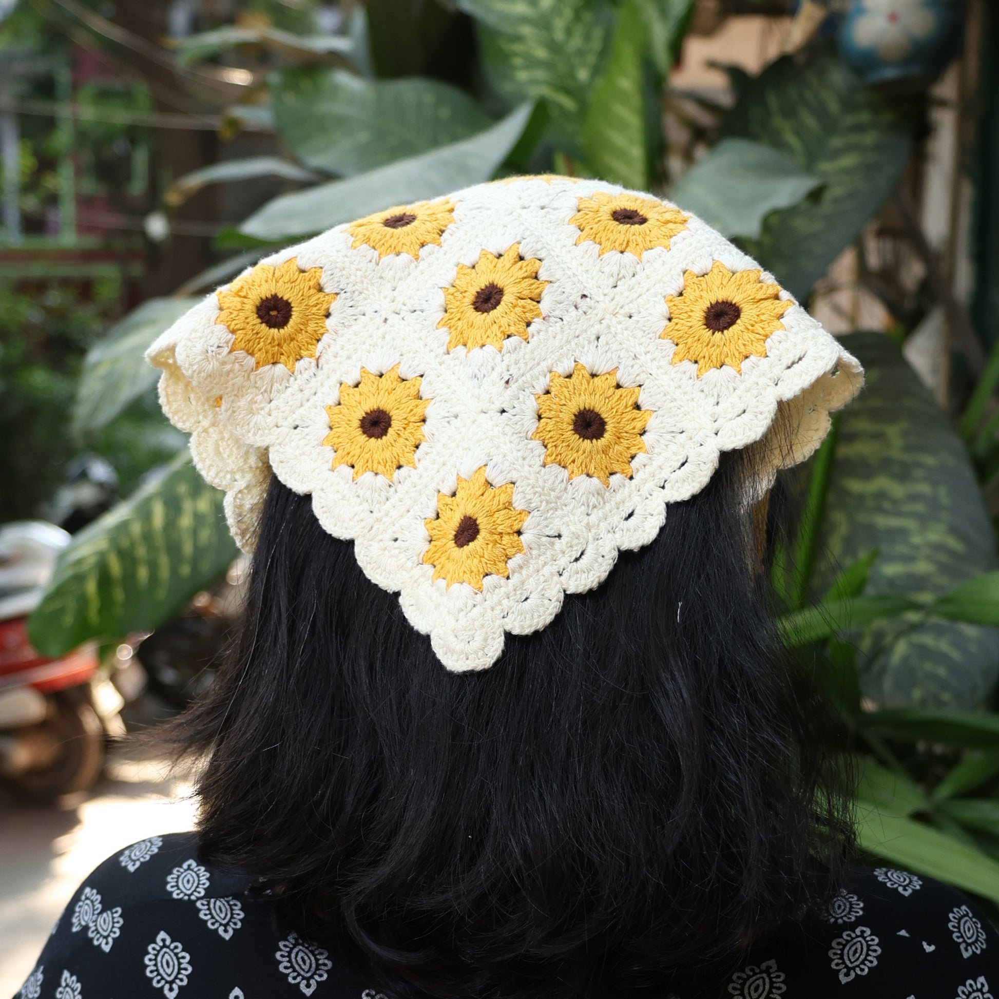 Sunflower crochet bandana in cream with yellow sunflowers worn on black hair outdoors