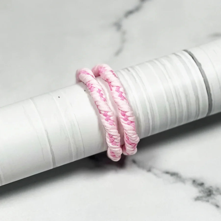 Pink fabric wrapped thick hair ties placed on a textured white cylindrical object