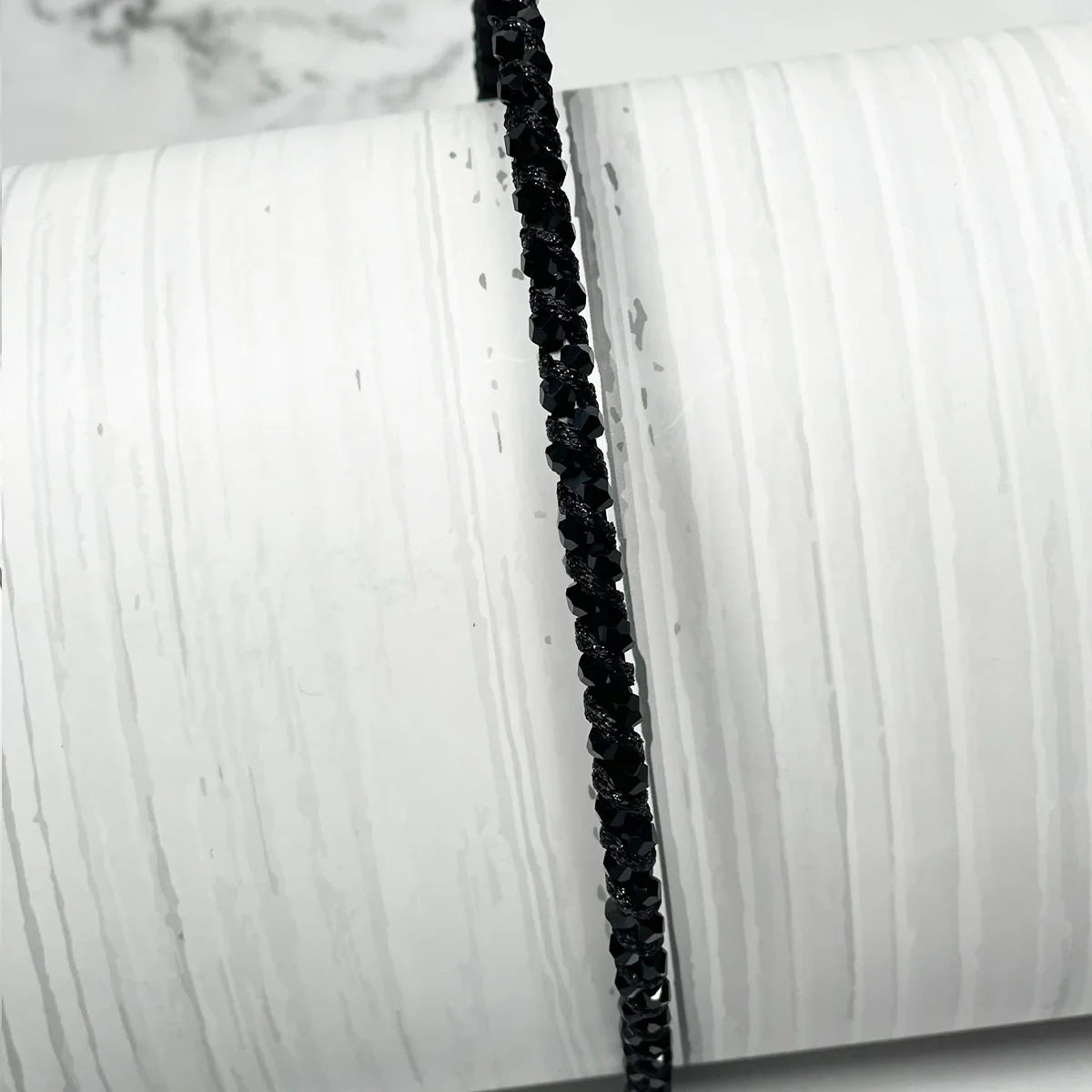 Black thin embellished headbands for women with sparkling beads displayed on white textured background