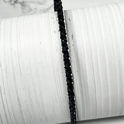 Black thin embellished headbands for women with sparkling beads displayed on white textured background