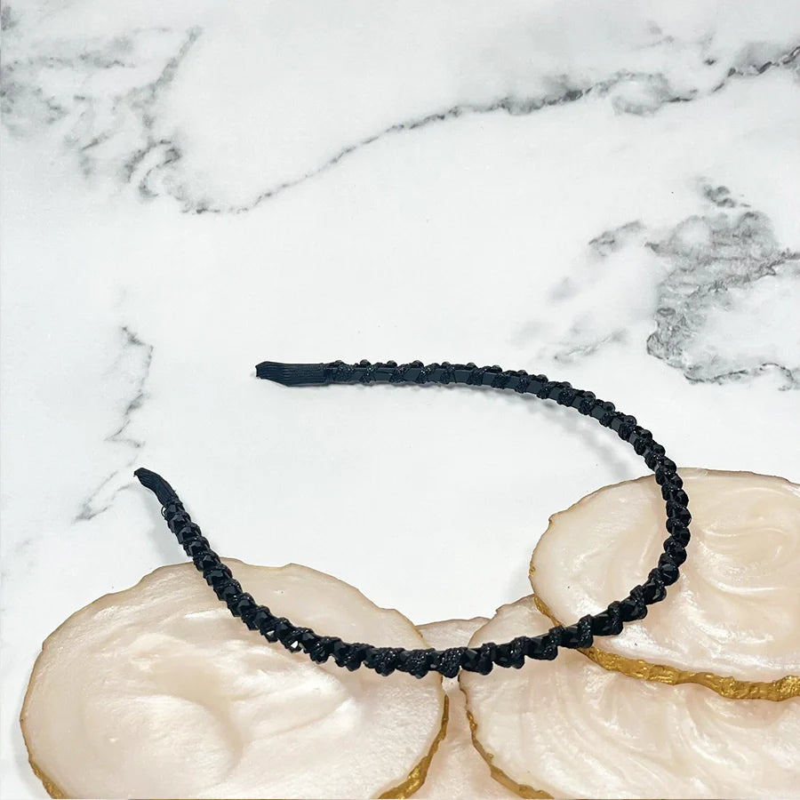 Black thin embellished headbands for women braided design on white marble background