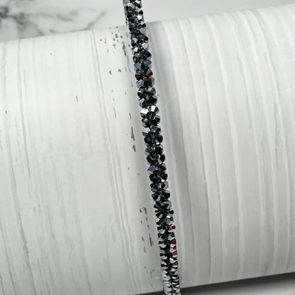 Black thin embellished headbands for women with sparkling crystals displayed on a white textured background