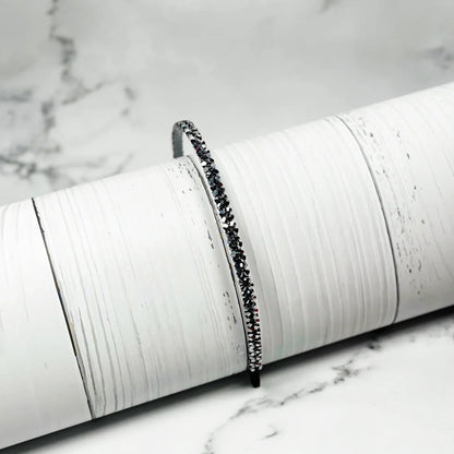 Black thin embellished headbands for women with sparkling stones on white textured background