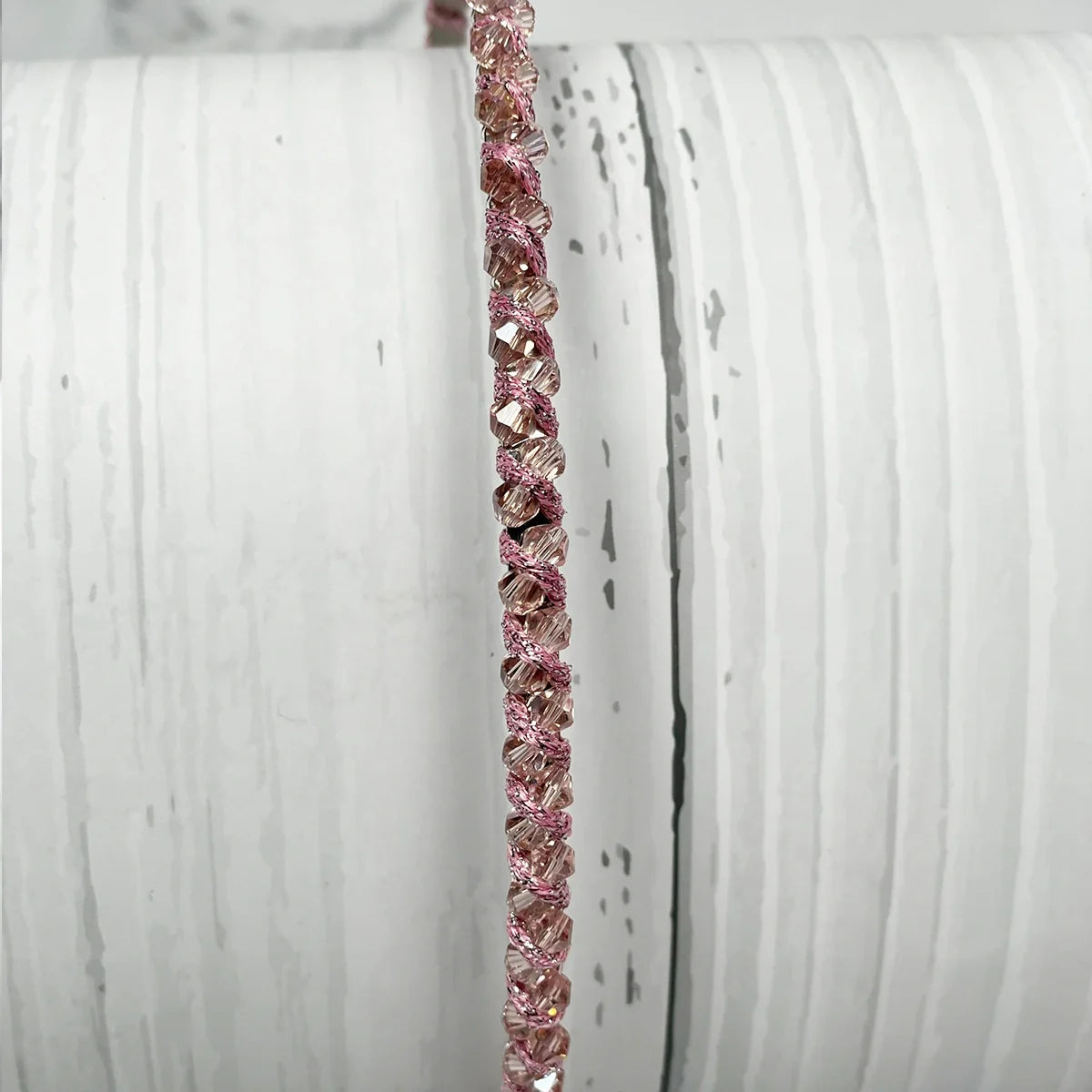 Close-up of thin embellished headbands for women in pink with sparkling details on a white textured background