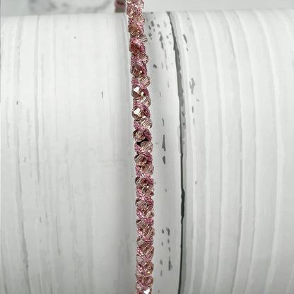 Close-up of thin embellished headbands for women in pink with sparkling details on a white textured background
