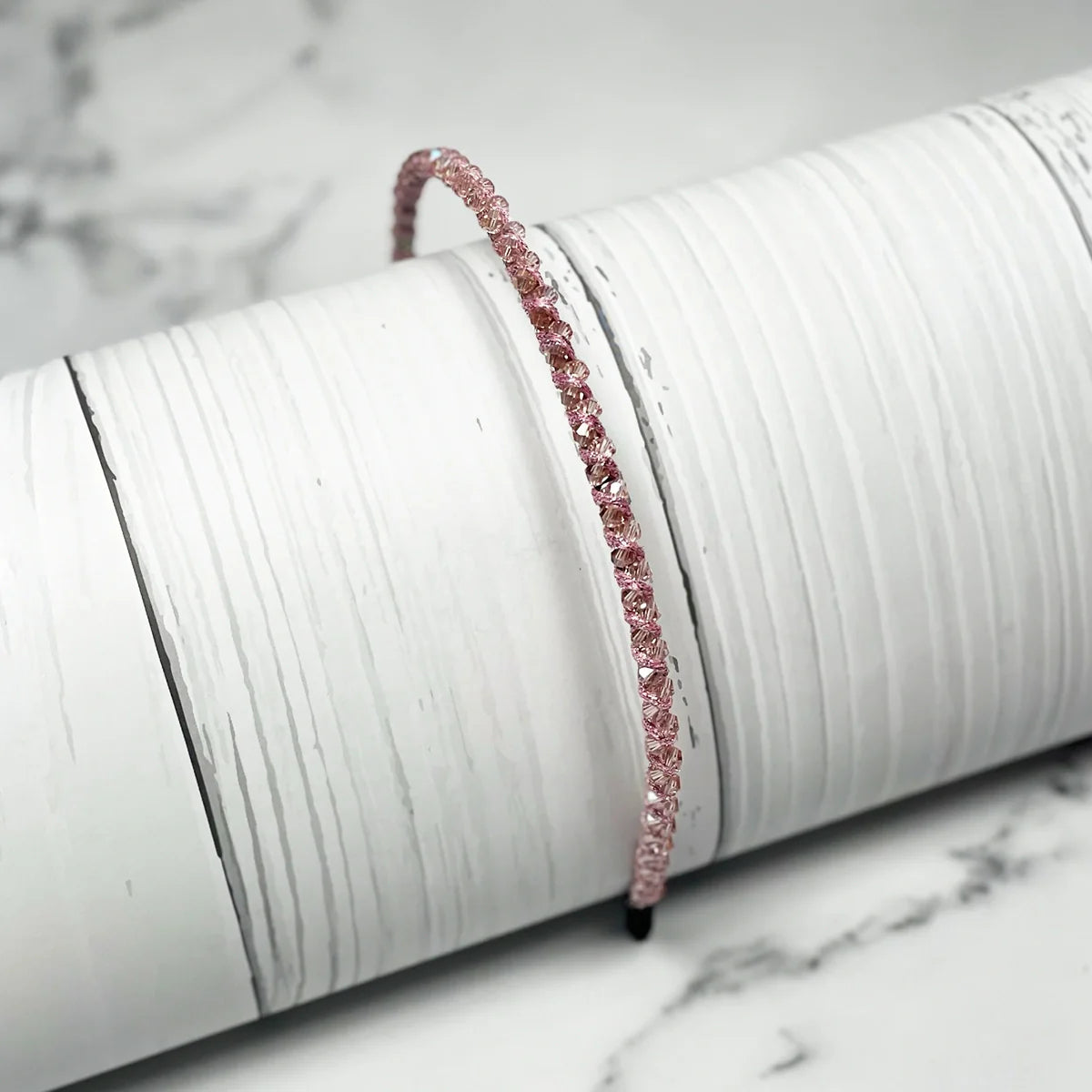 Pink thin embellished headbands for women with sparkling rhinestones on a white textured surface