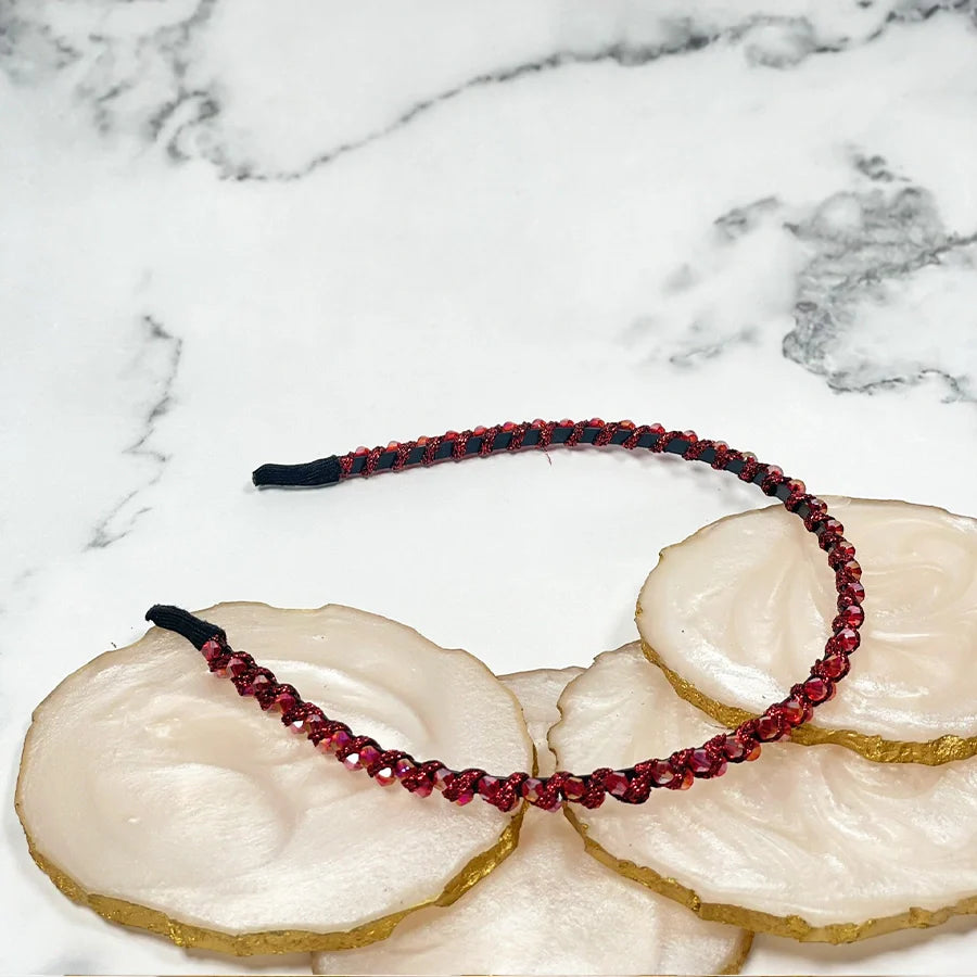 Red thin embellished headbands for women with sparkling details on a marble background