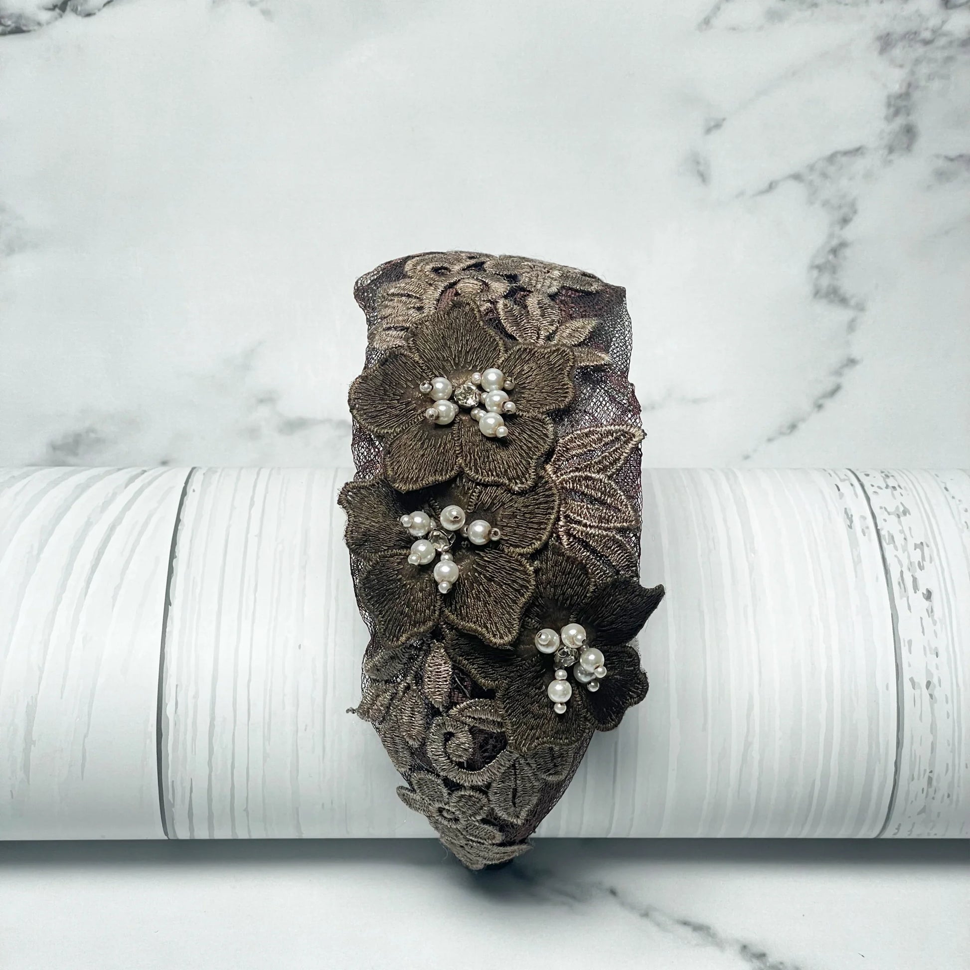 Three flower broad hairbands featuring brown lace and pearl embellishments on a white wooden background