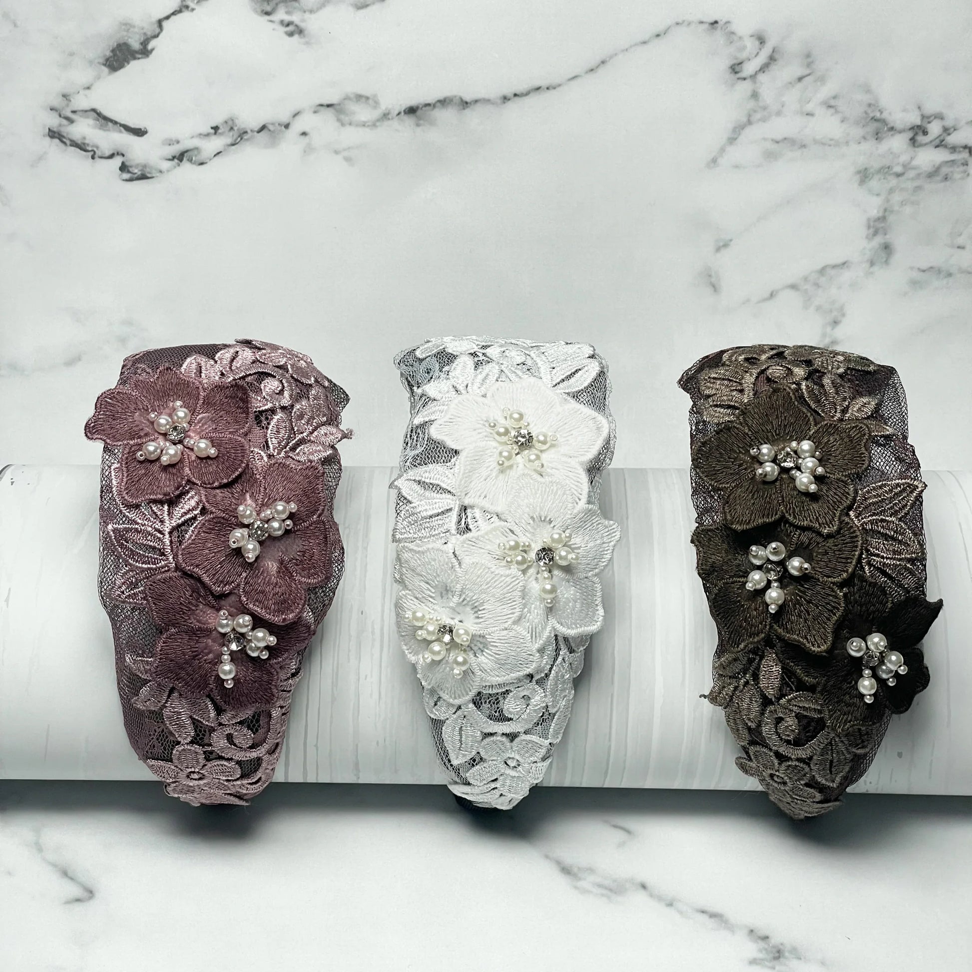 Three flower broad hairbands in pink, white, and brown with lace and pearl accents