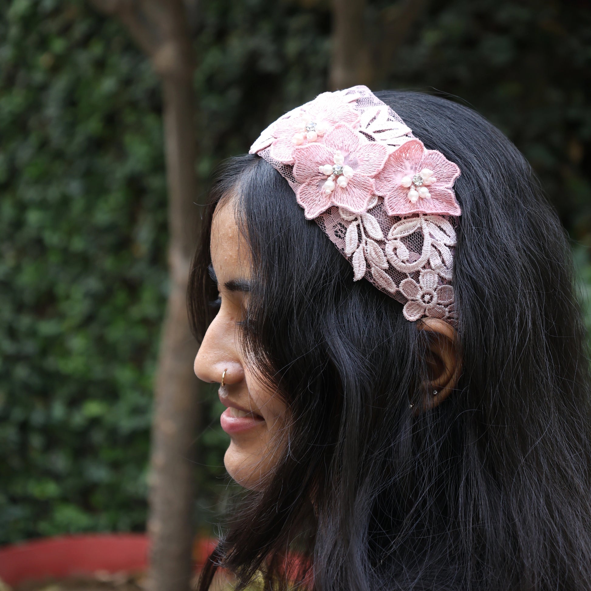 Woman wearing pink lace three flower broad hairbands with decorative floral design outdoors
