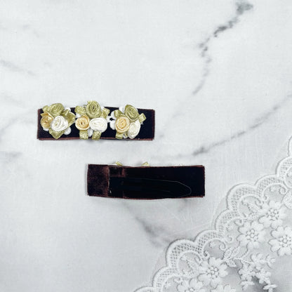 Velvet flower hair pins with small yellow and white rose designs on dark velvet base