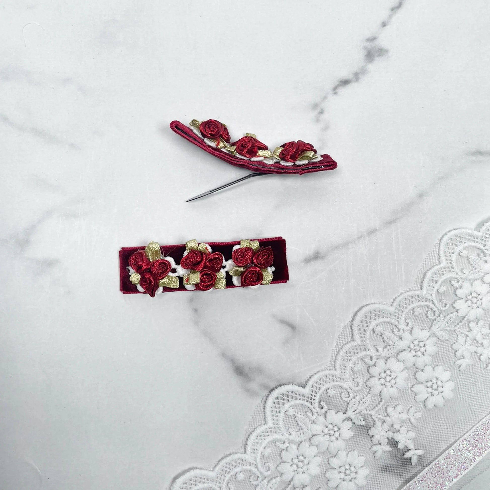 Red velvet flower hair pins with small roses and green leaves on white lace background