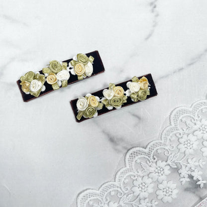 Velvet flower hair pins with cream and green floral design on dark velvet background