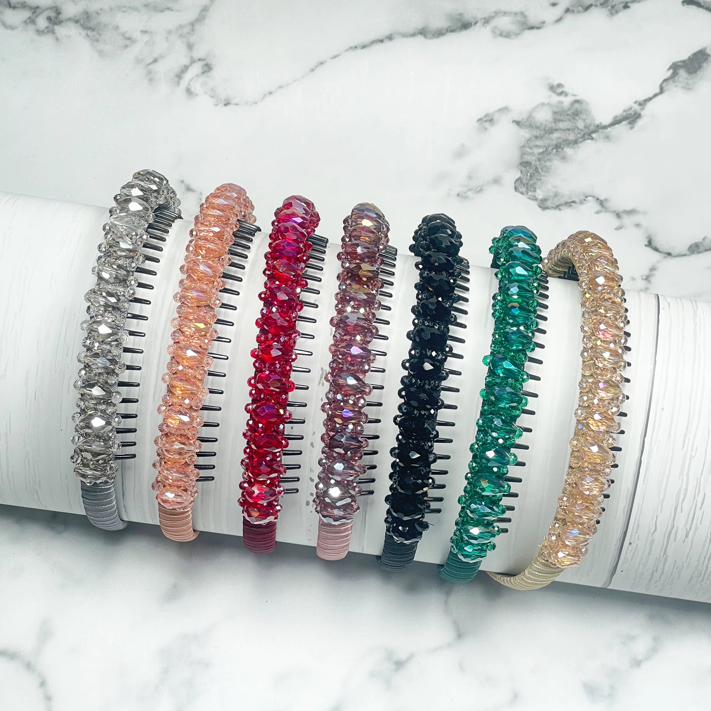 Assorted Heavy Crystal Embellished Hairbands in various colors displayed on a white marble background