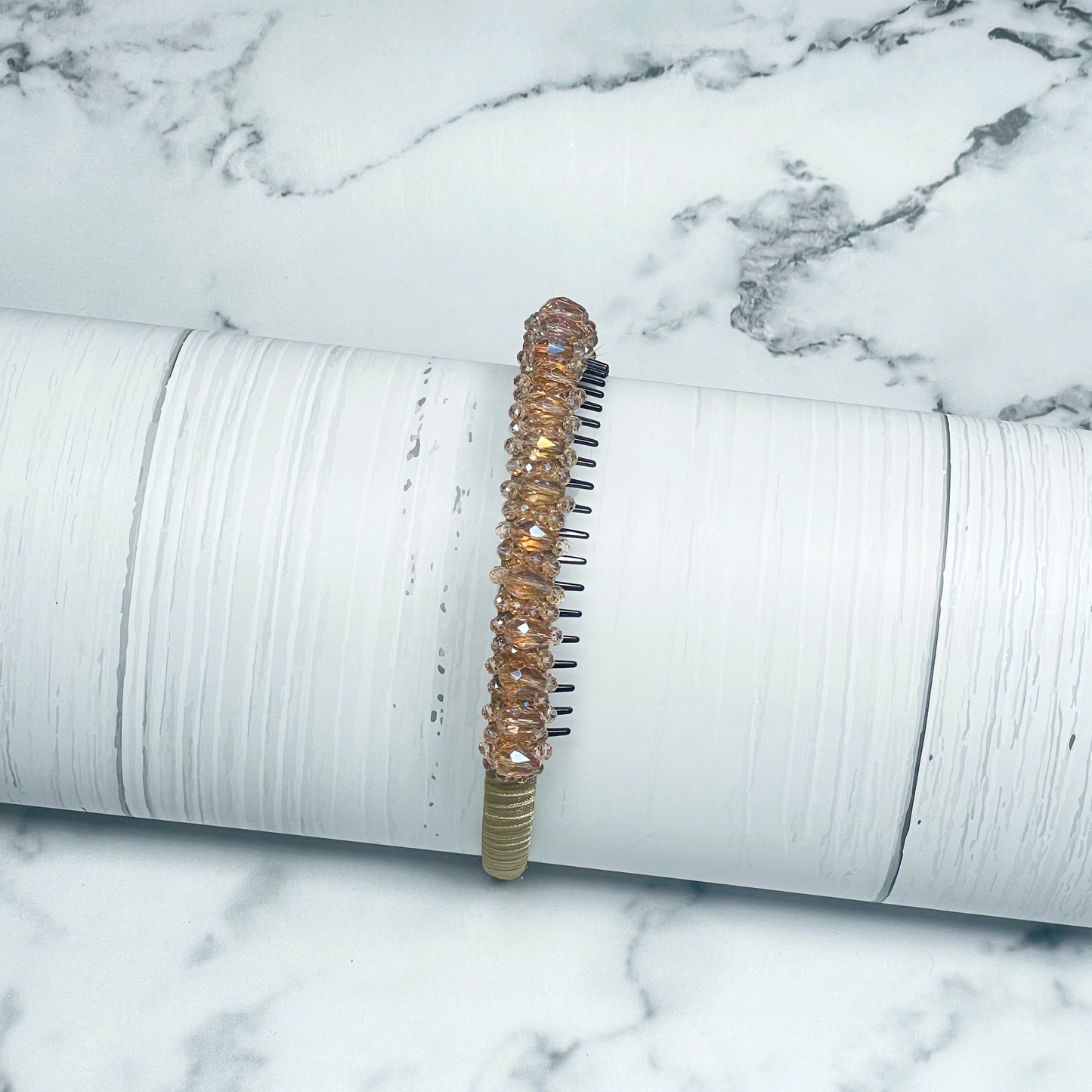Elegant heavy crystal embellished hairbands in light amber with a sparkling design on white wooden surface