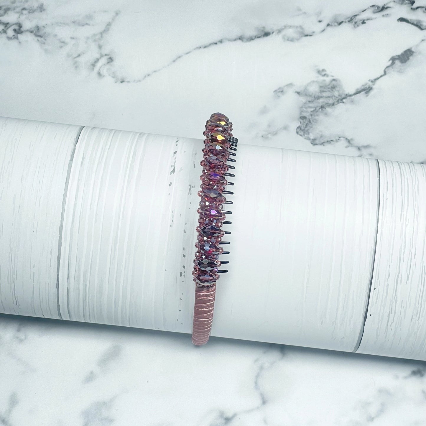 Pink heavy crystal embellished hairbands with sparkling beads on a white textured background