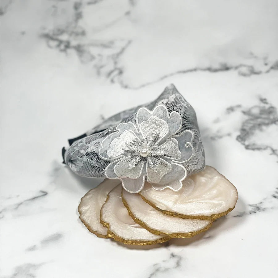 Gray lacy embellished hairbands for women with floral design and pearl details on marble background