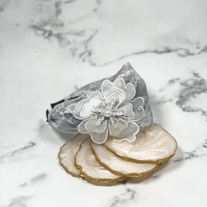 Gray lacy embellished hairbands for women with floral design and pearl details on marble background