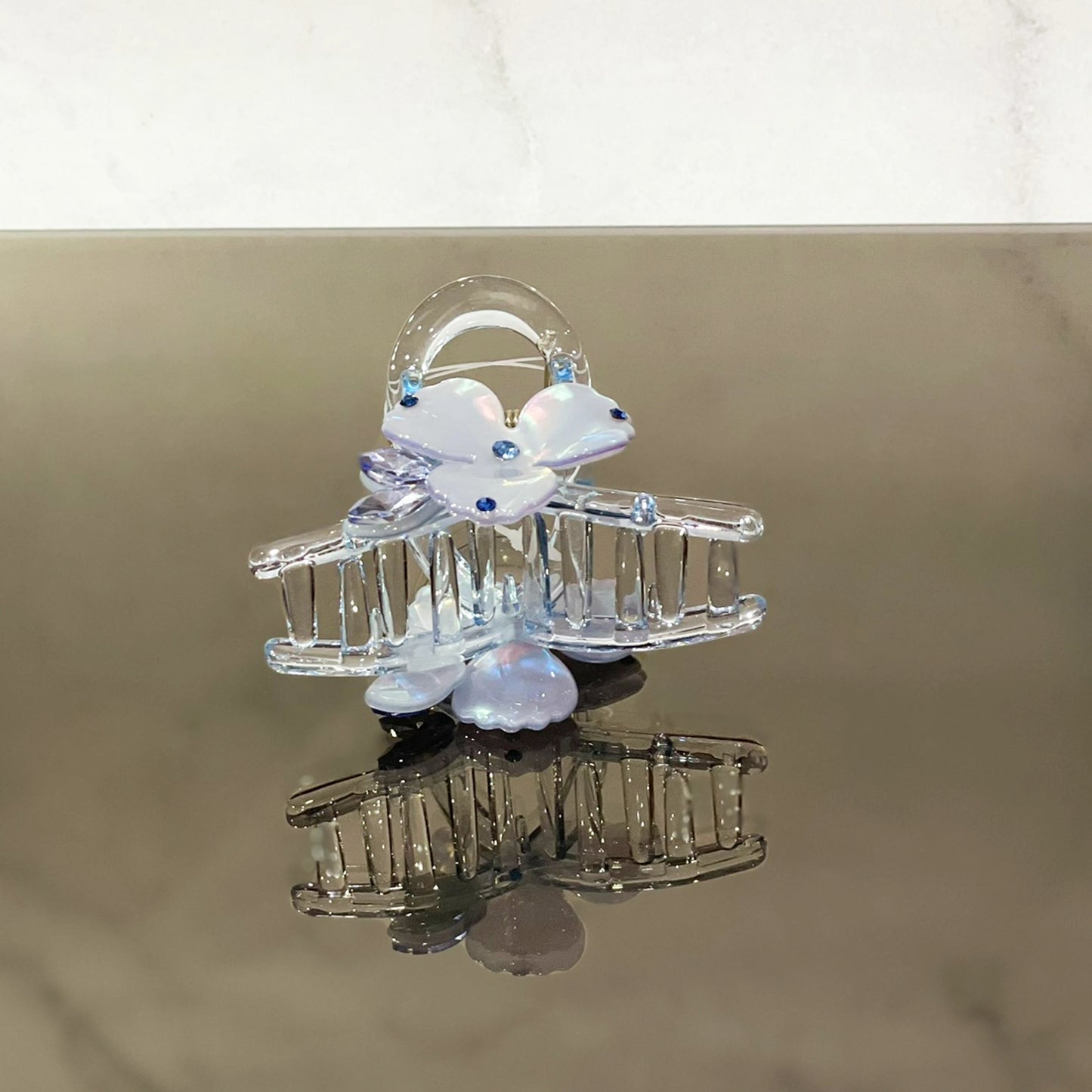 Clear pearl studded flower hair clutch with blue accents on reflective surface