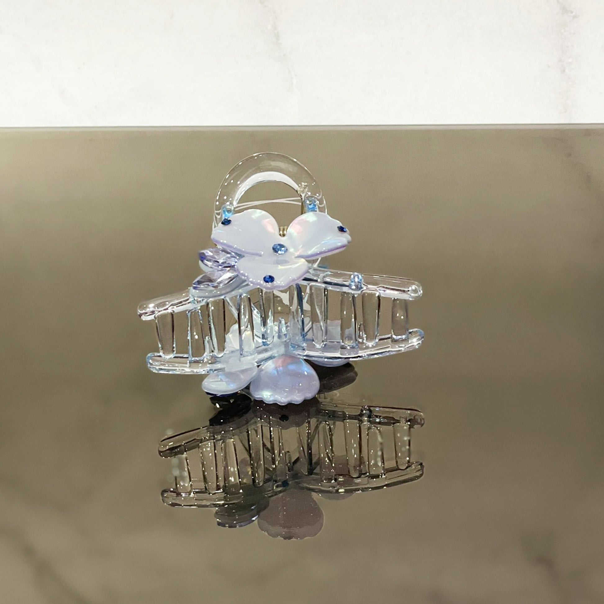 Clear pearl studded flower hair clutch with blue accents on reflective surface
