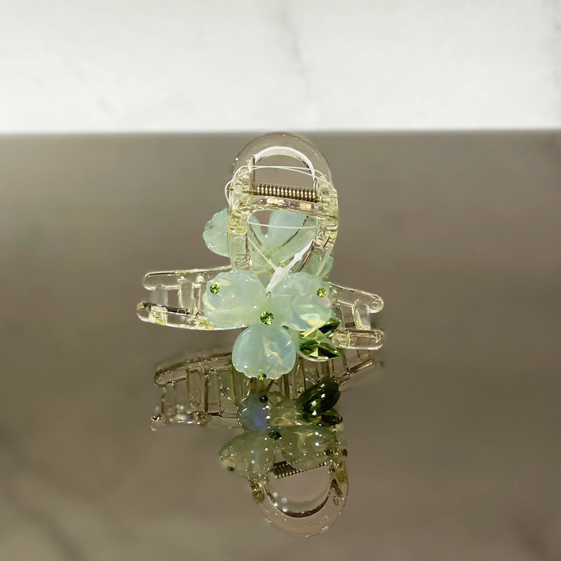 Pearl studded flower hair clutch with translucent petals and small green accents for elegant styling