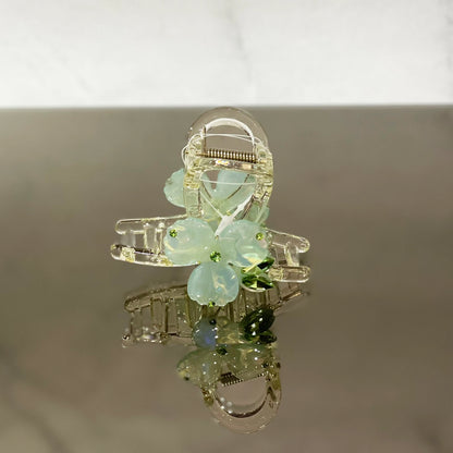 Pearl studded flower hair clutch with translucent petals and small green accents for elegant styling