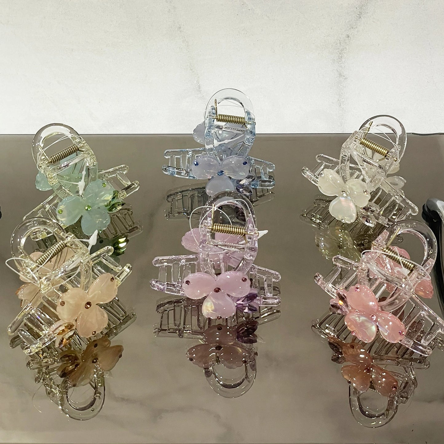 Pearl studded flower hair clutch in pastel colors including pink, blue, green, and white on reflective surface