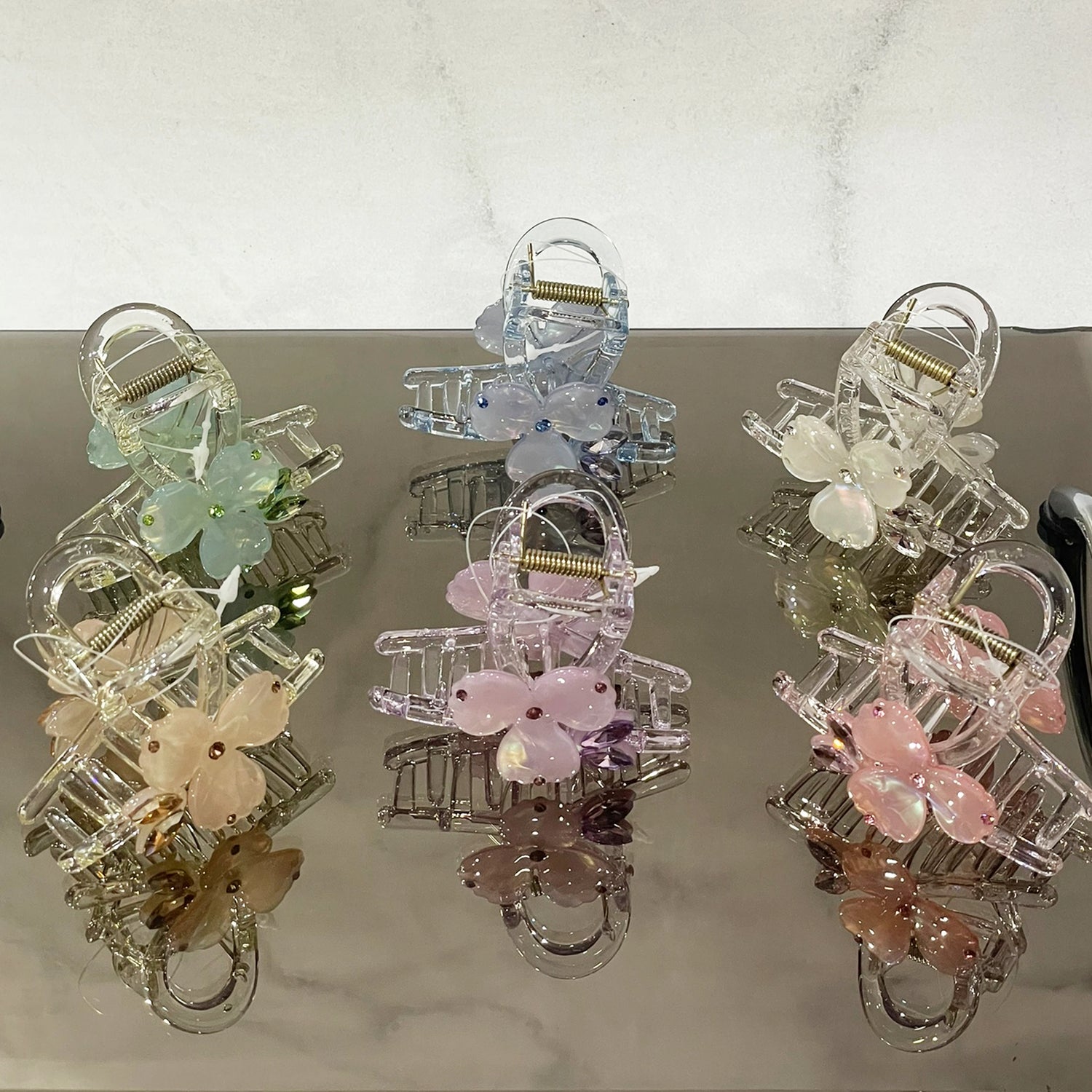 Pearl studded flower hair clutch in pastel colors including pink, blue, green, and white on reflective surface