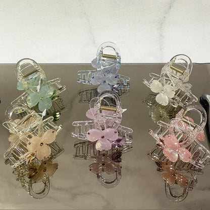 Pearl studded flower hair clutch in pastel colors including pink, blue, green, and white on reflective surface