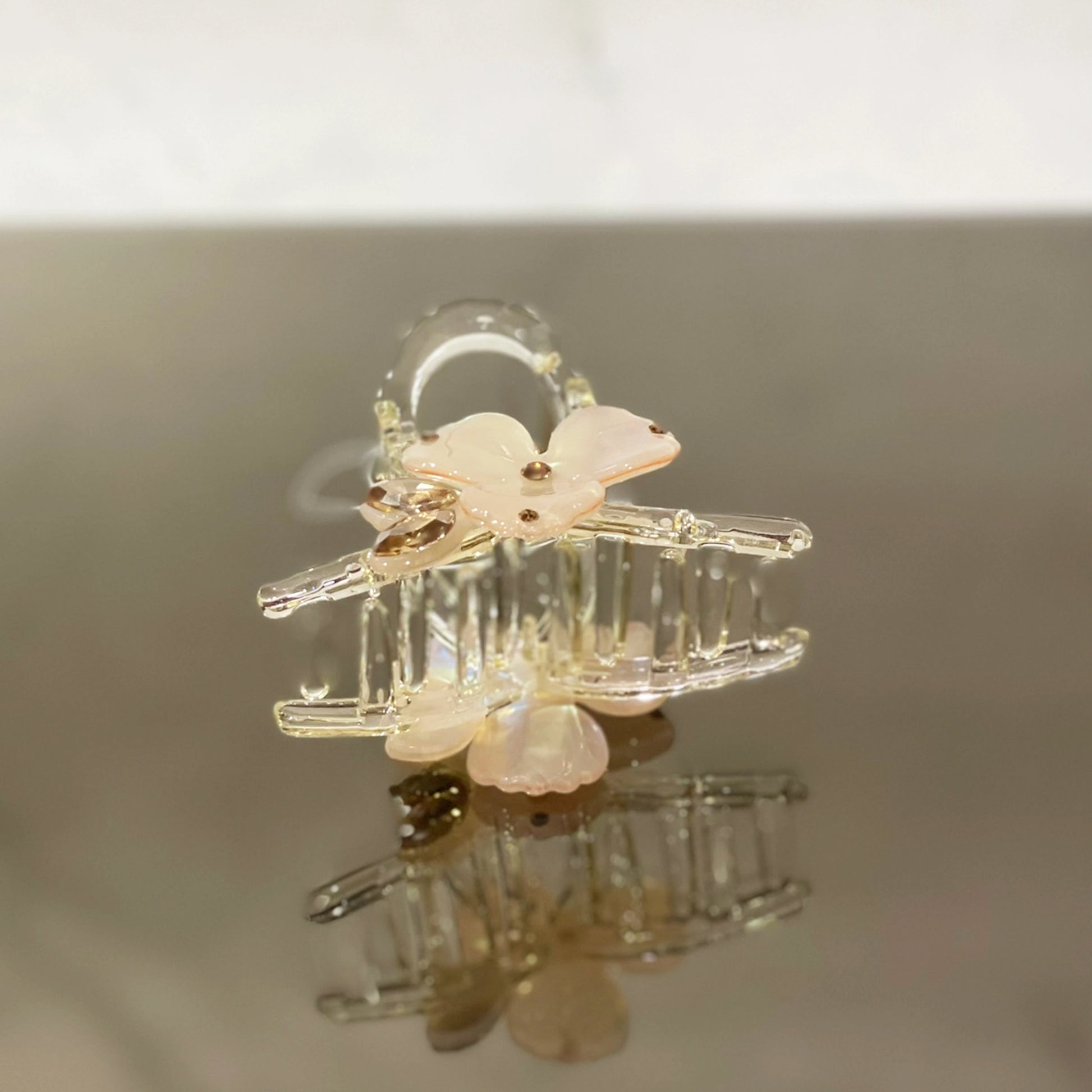 Clear pearl studded flower hair clutch with pink flower design on reflective surface