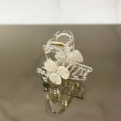 Clear pearl studded flower hair clutch with white pearl petals on reflective surface