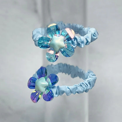 Light blue shiny daisy flower hair ties with iridescent petals on elastic bands
