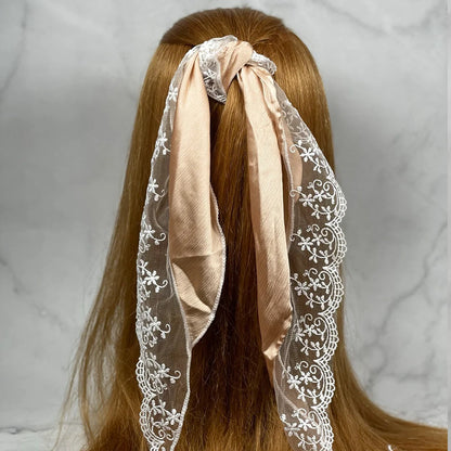 Synthetic Lacy Hair Scarf in beige with white floral lace tied around long brown hair
