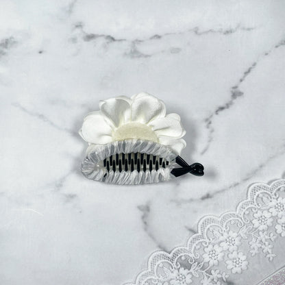 Bella Luxe white crystal banana clip with flower design on marble background