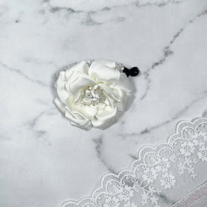 Bella Luxe white crystal banana clip with flower design on marble surface and lace fabric