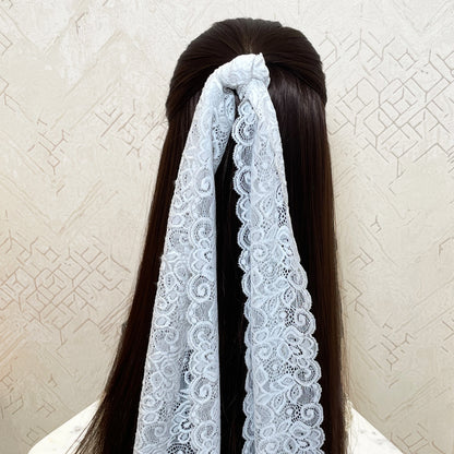 White lacy hair scarf tied around long dark hair with intricate lace patterns by Bella Luxe